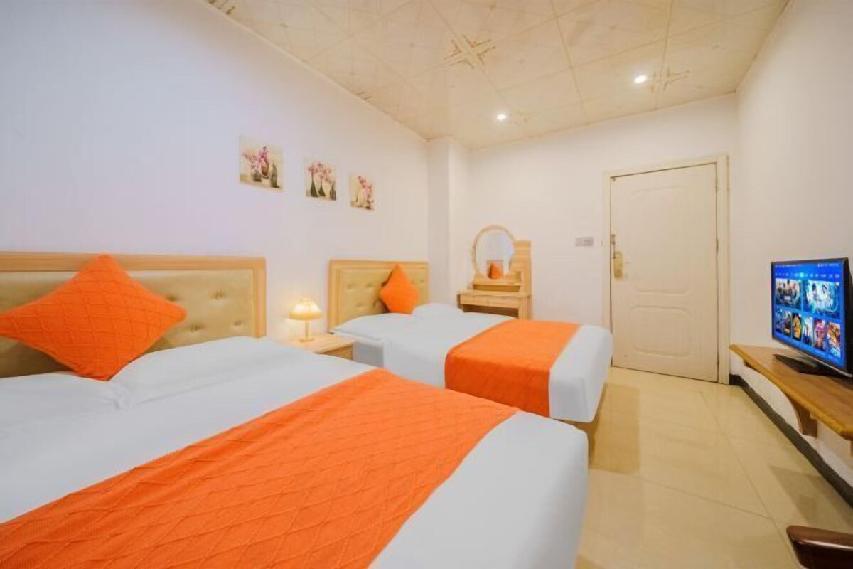 A hotel room with two beds, a television, and a door.