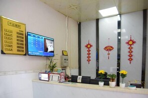 A reception area with a computer monitor, a telephone, and a reception desk. - Puning Shi Hai Apartment (Puning)
