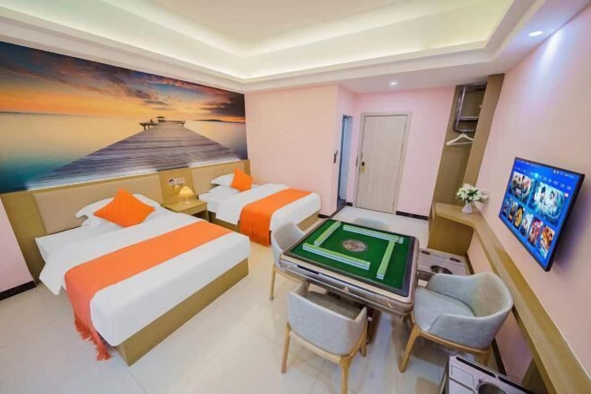 A hotel room with two beds, a pool table, a TV, and a mural of a pier.