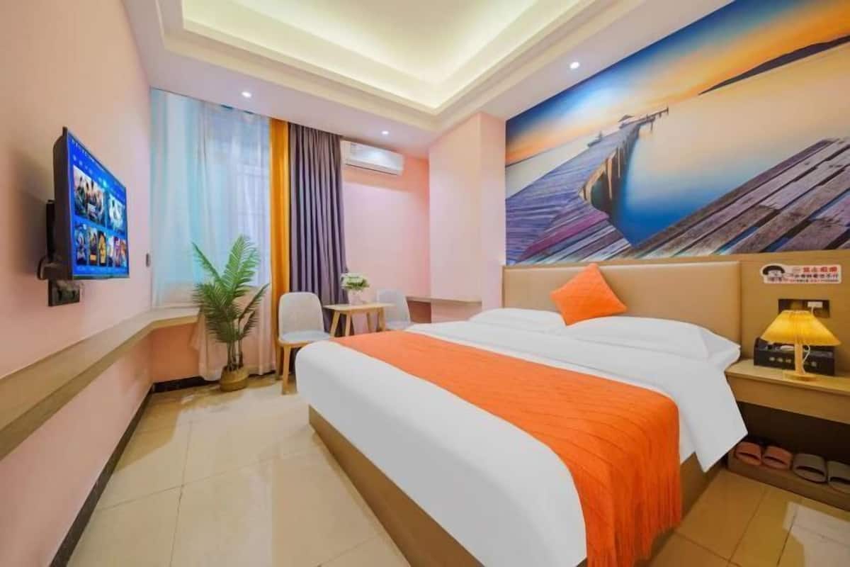 A hotel room with a bed, a desk, a chair, a TV, and a painting on the wall.