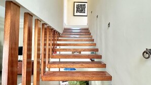 A wooden staircase with a modern design, leading to a landing with a framed artwork. - Unique Moroccan Style Villa in Golf Beach Resort (Punta Cana)