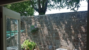 An outdoor patio with a stone wall, potted plants, and metal furniture. - Ground Floor Bodmin Retreat Free Parking (Bodmin)