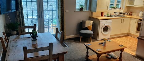 A compact living space with a dining area, a sofa, a washing machine, and a kitchen area.