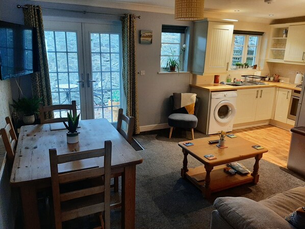 Un espacio habitable compacto con comedor, sofá, lavadora y zona de cocina.