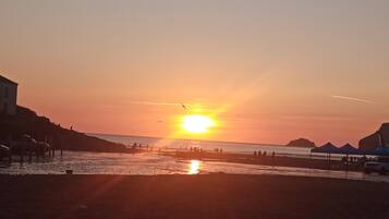Un coucher de soleil sur une plage, avec des personnes et des tentes.