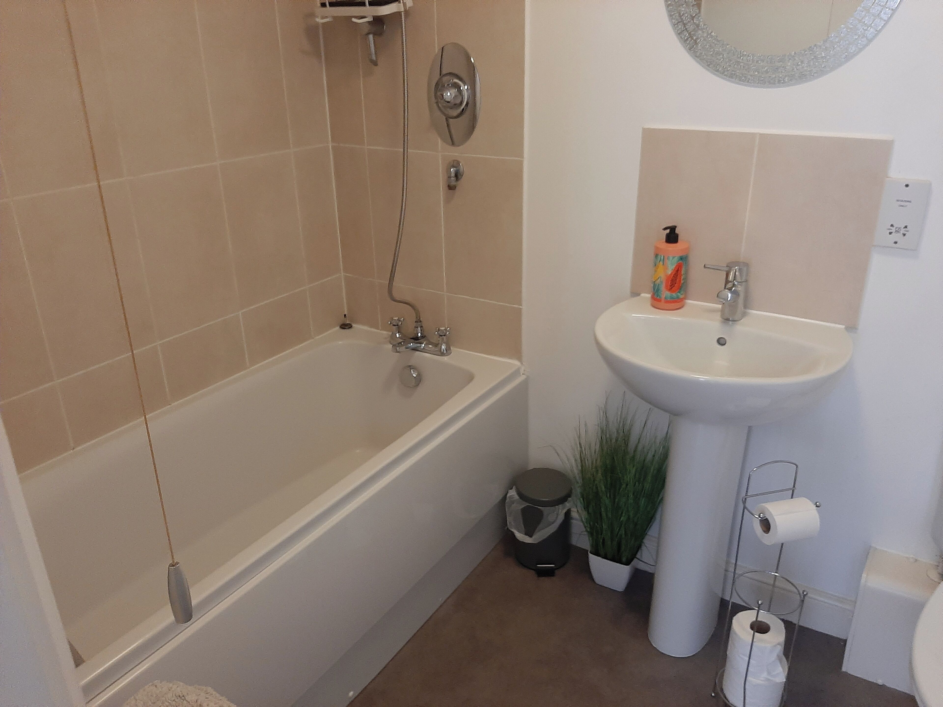 A bathroom with a bathtub, a sink, a toilet, and a trash can.