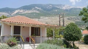 A small, single-story house with a tiled roof, a balcony, and a satellite dish. - Villa Delphia One Bedroom Traditional House (Kefalonia)