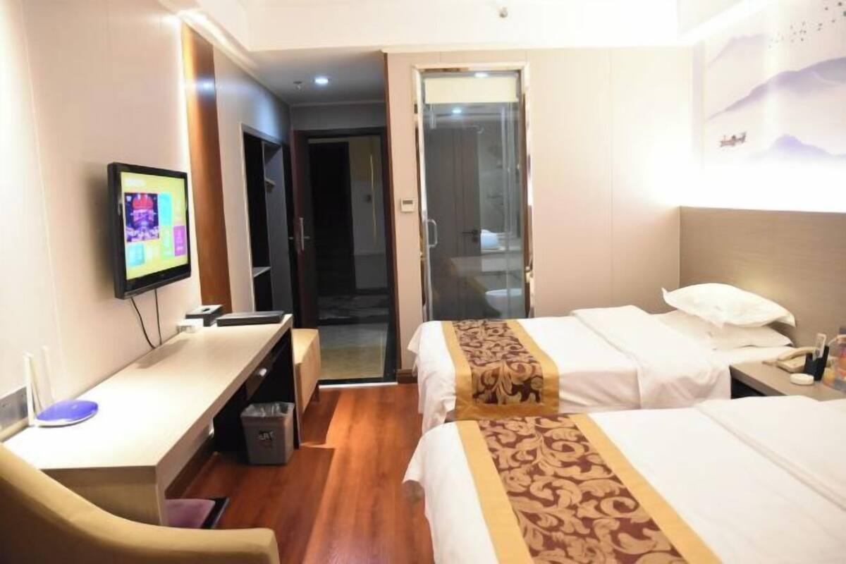 Una habitación de hotel con una cama, un escritorio con una computadora, una silla y un televisor.