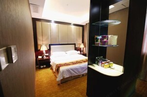 Una habitación de hotel con cama, lámparas de noche, mesita de noche, espejo y estante con artículos de aseo.