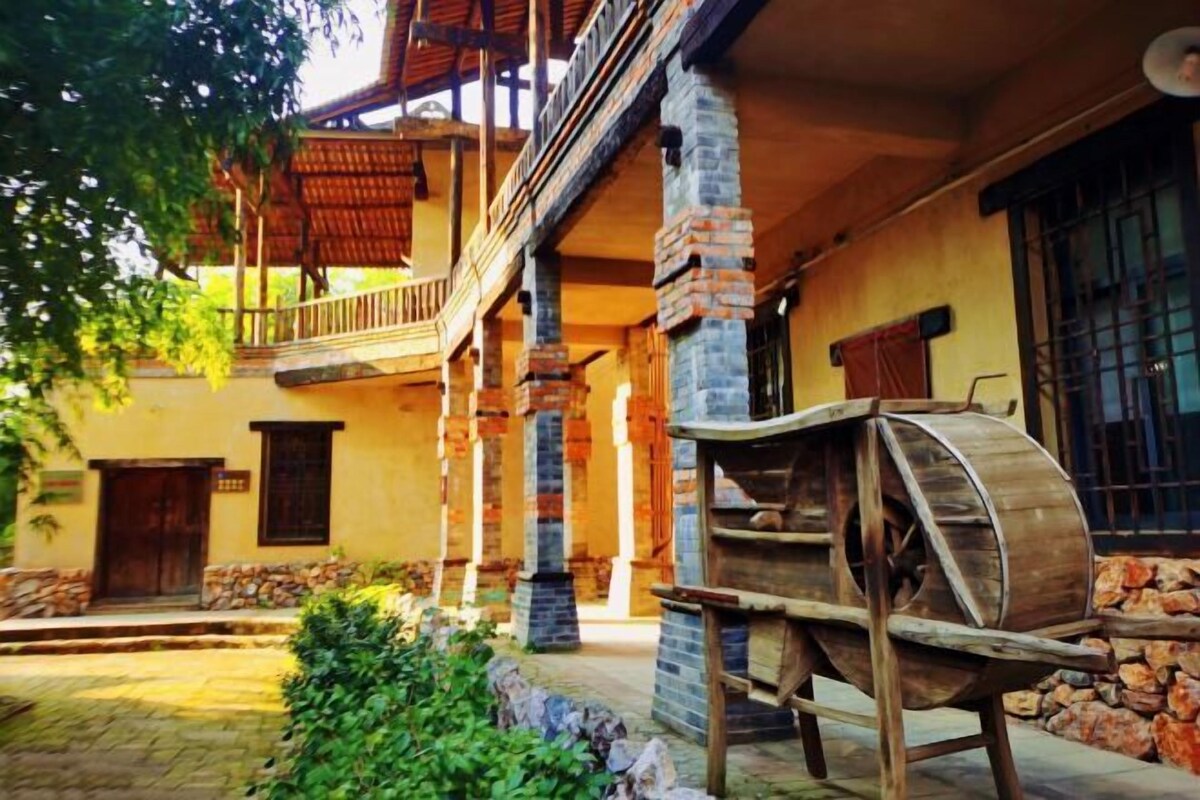 A building with a balcony, a wooden barrel, and a stone wall.