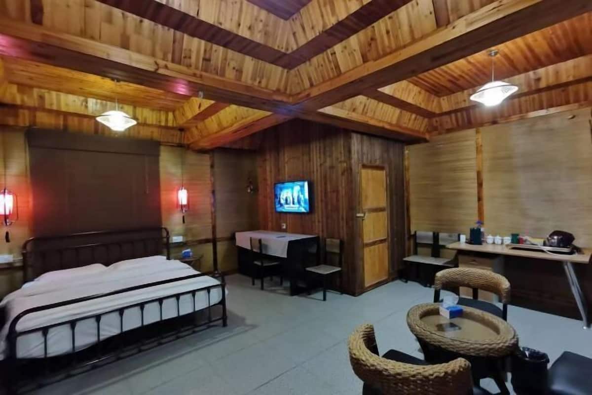 Un intérieur en bois comprenant un lit, une table, des chaises, un téléviseur et un bureau.