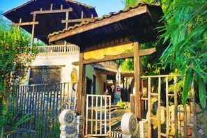 A traditional wooden structure with a gate, surrounded by lush greenery. - Huaqitang Rural Life Hostel (Wuhan)