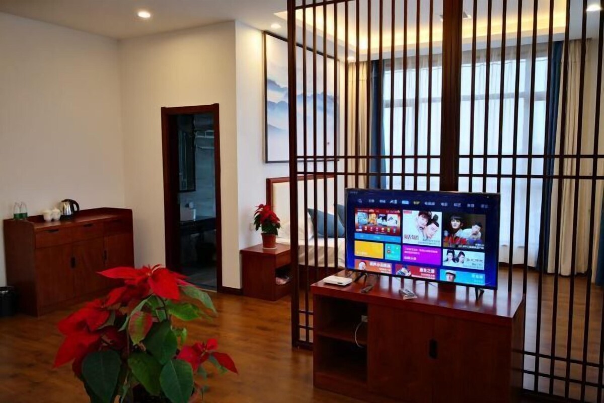 A room with a wooden TV stand, a potted plant, and a sliding door.