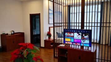 A room with a wooden TV stand, a potted plant, and a sliding door.