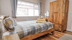 Un dormitorio con cama de madera, un armario, una mesita de noche y una ventana con cortinas.