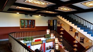 A staircase with traditional lanterns and a reception desk with plants. - Wuming Inn (Dali City)