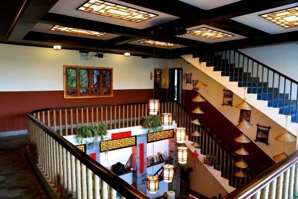 A staircase with traditional lanterns and a reception desk with plants.