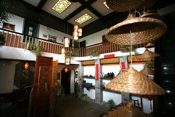 A traditional interior with a central staircase, hanging woven lamps, and decorative elements. - Wuming Inn (Dali City)