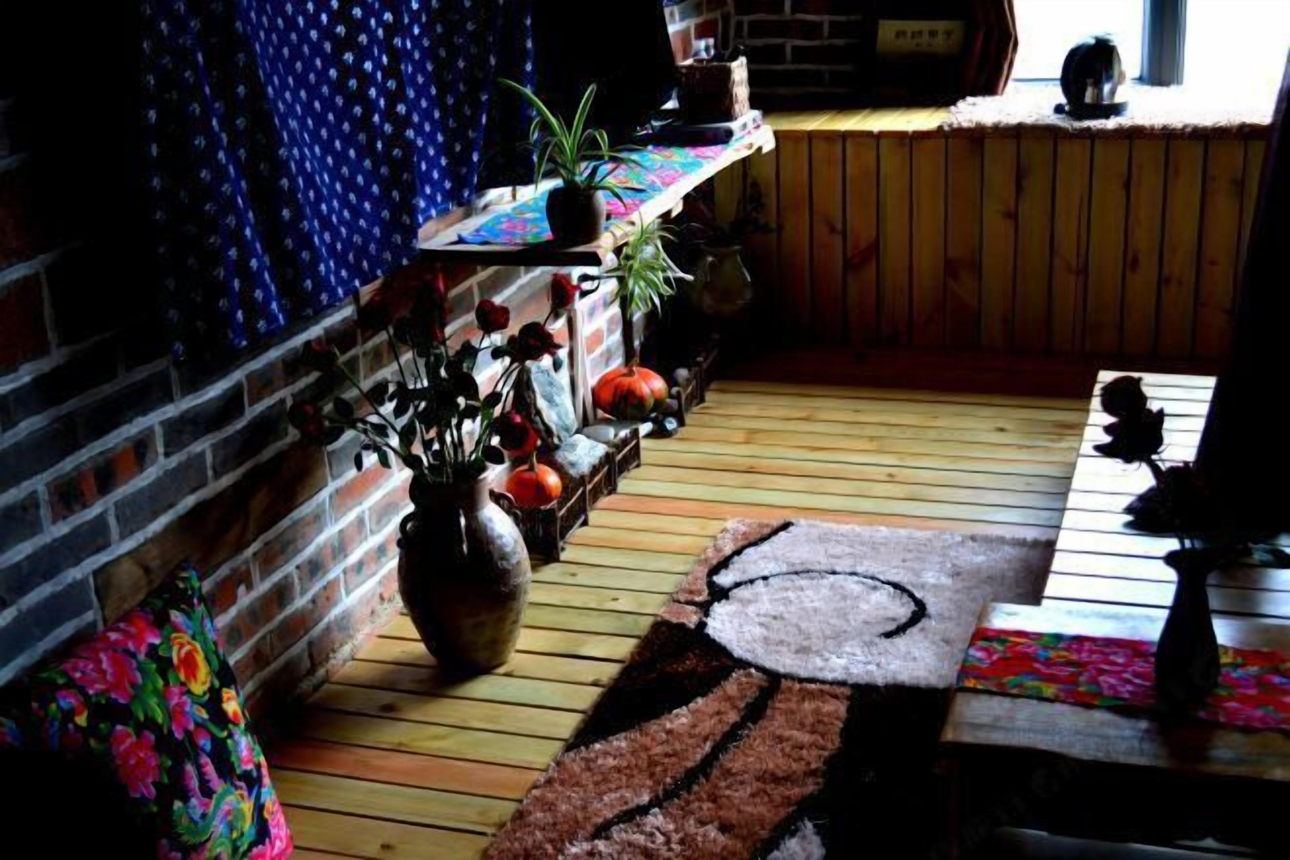 A cozy room with a wooden floor, a brick wall, and a window with blinds.