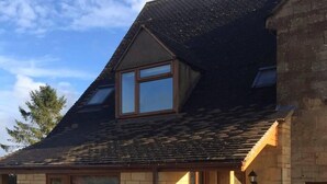 A two-story house with a sloped roof, a brick exterior, and a small porch with a wooden door. - Blacklaines Annexe Birdlip - Pet Friendly! (Gloucester)