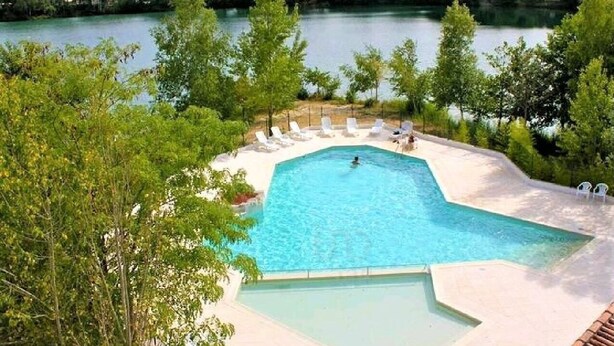 A swimming pool surrounded by lounge chairs and trees, with a view of a lake. - Vacation rental near Royan in a magnificent setting (sainte gemme)