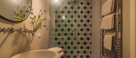 A bathroom with a white sink, a glass shower enclosure, and a towel rack.