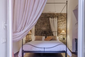 Ein Bett mit Blick auf eine Steinwand, einem Baldachin und Nachttischlampen.
