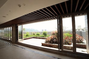 A corridor with large windows, a view of greenery, and a modern ceiling design. - Guangling Nanfan Hotel (Lingshui)