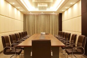 Uma sala de conferências com uma mesa comprida, cadeiras de couro marrom e um candelabro.
