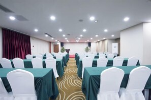 A conference room with rows of tables and chairs, a carpeted floor, and a stage at the front. - Aixi Jialin Hotel(Chongqing Bishan Junhao Central Street Store) (Chongqing)