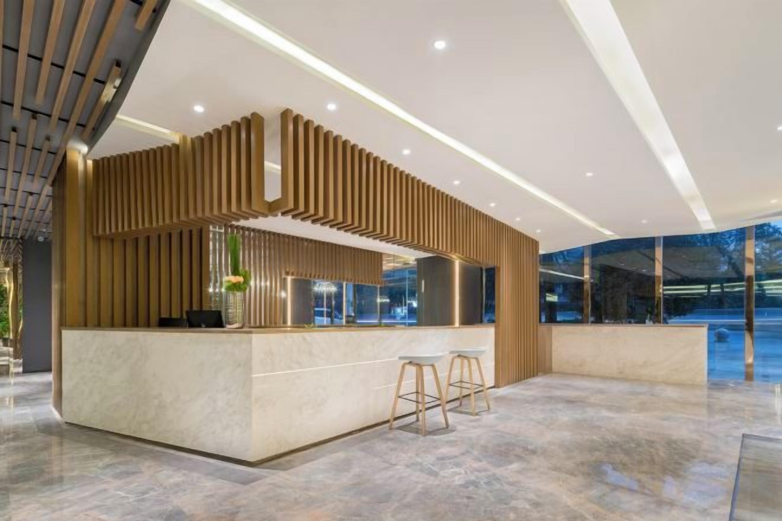 Una moderna zona de recepción con suelo de mármol, mostrador de madera y separador de vidrio.