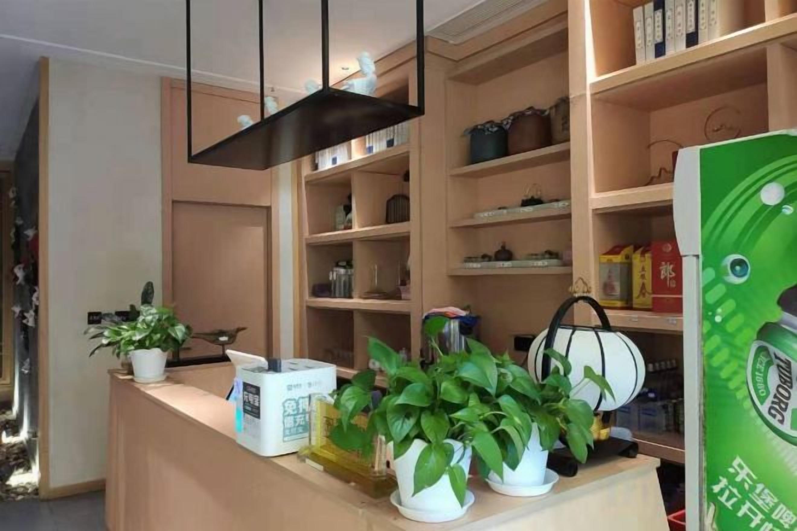 A reception area with a counter, potted plants, and shelves with various items.