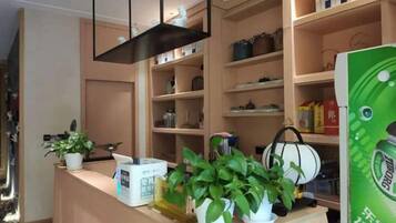 A reception area with a counter, potted plants, and shelves with various items.