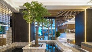 A lobby with a central water feature, a tree, and a modern design with dark walls and wooden accents. - Aixi Jialin Hotel(Chongqing Bishan Junhao Central Street Store) (Chongqing)