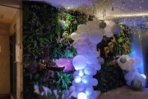 Et rum med en grøn væg, en buet ballonkrans i hvid og sort, og et skilt med teksten 'Happy New Year'.