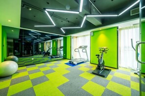 A gym with exercise equipment, a mirrored wall, and a checkered floor. - Aixi Jialin Hotel(Chongqing Bishan Junhao Central Street Store) (Chongqing)
