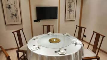 Mesa de jantar redonda com tampo de vidro e peça decorativa central, rodeada por cadeiras de madeira.