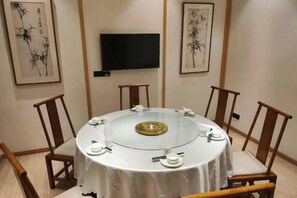 Une table de salle à manger ronde, avec un plateau en verre et un élément décoratif central, entourée de chaises en bois.