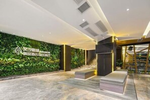 Un vestíbulo con pared verde, mostrador de recepción y escalera.