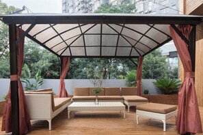 A covered outdoor seating area with a table and chairs, surrounded by curtains. - Aixi Jialin Hotel(Chongqing Bishan Junhao Central Street Store) (Chongqing)