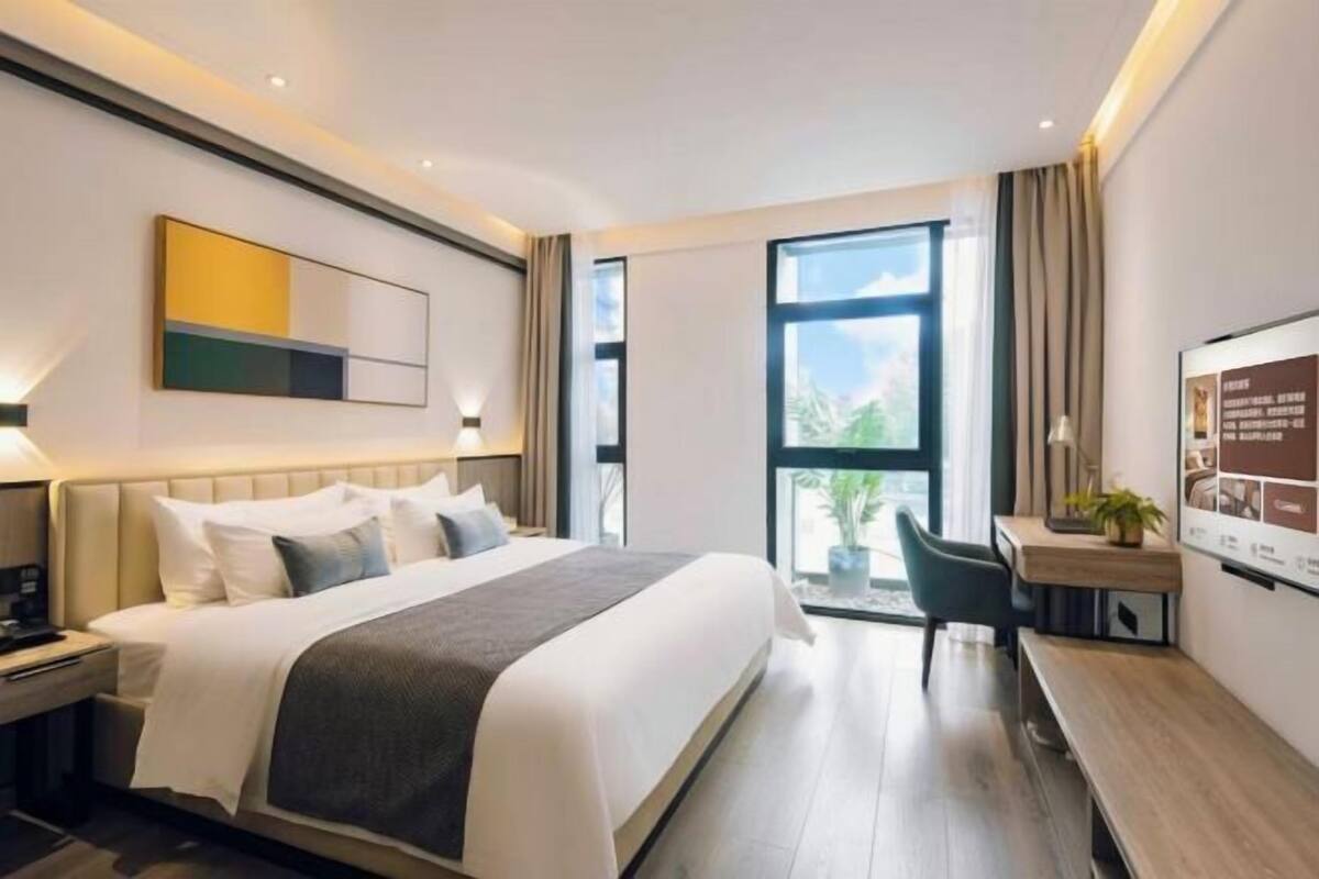Ein modernes Hotelzimmer mit einem großen Bett, einem Schreibtisch und Blick ins Freie.