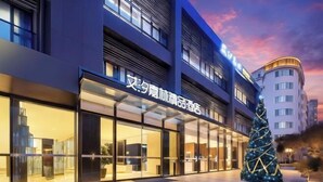 A modern hotel with large glass windows, a prominent Christmas tree, and a sign with Chinese characters. - Aixi Jialin Hotel(Chongqing Bishan Junhao Central Street Store) (Chongqing)