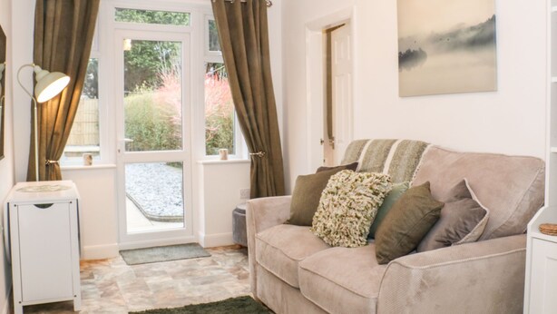 A cozy living room with a beige sofa, a lamp, and a painting on the wall. - Hope Cottage (Thornton-Cleveleys)