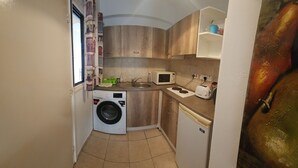 Uma cozinha compacta com máquina de lavar, micro-ondas, torradeira e pia.