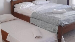 Quarto com duas camas de madeira, uma mesinha redonda e um vaso com planta.