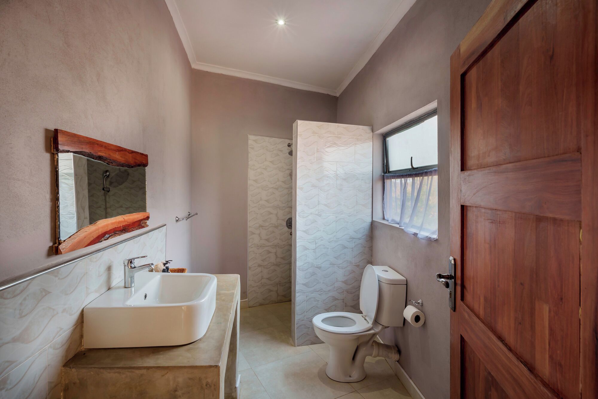 A bathroom with a large sink, mirror, toilet, and shower.