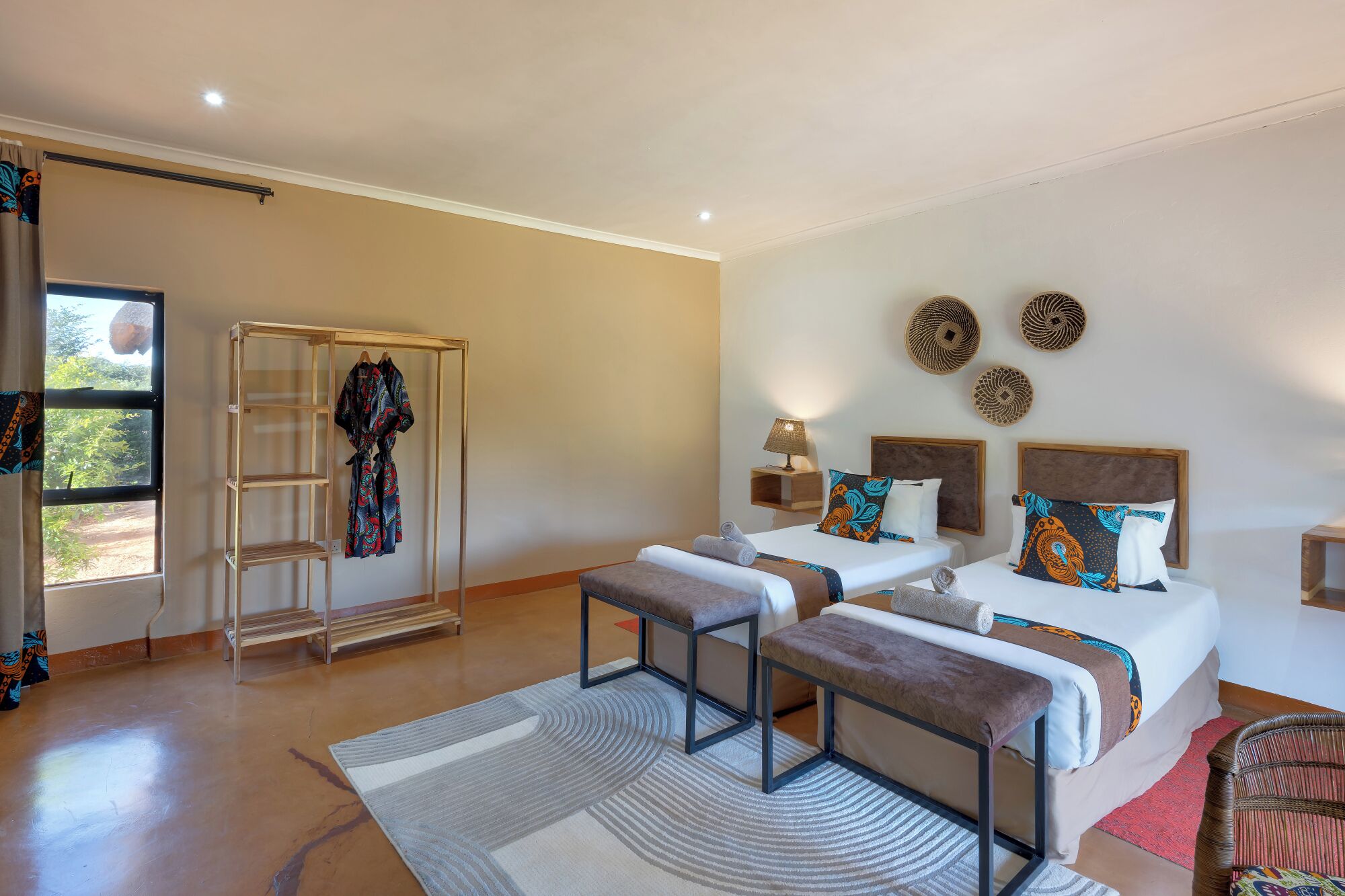 A hotel room with a bed, two bedside tables, a bench, a wardrobe, and a window with a view.