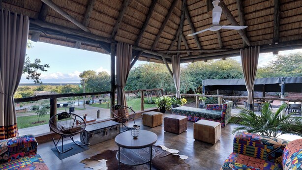 A covered outdoor seating area with a table, chairs, and a view of the landscape. - The Nkhosi Livingstone Lodge and Spa (Livingstone)