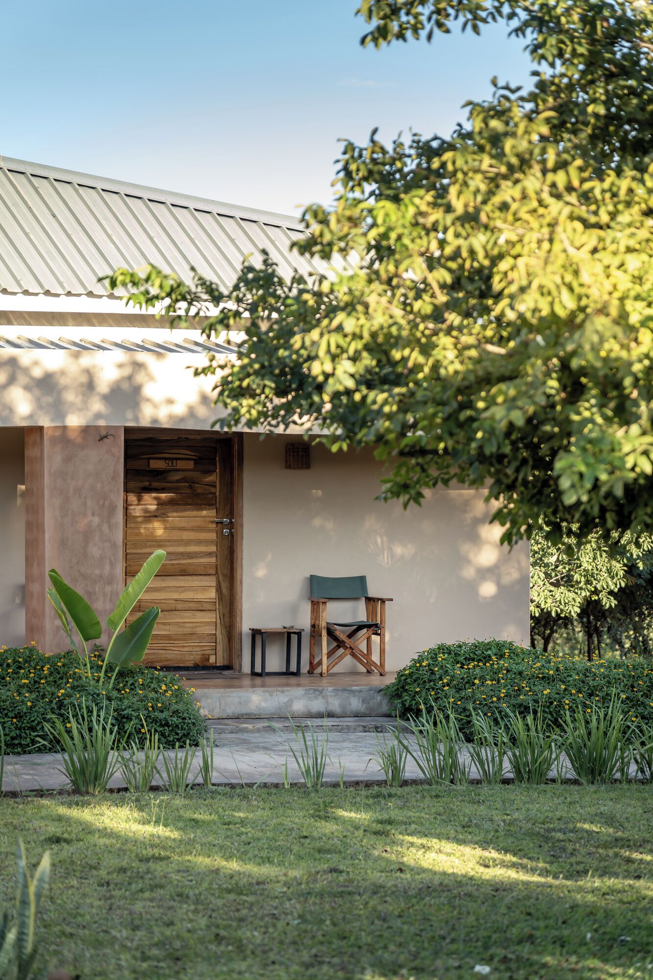 Une maison moderne avec une porte en bois, une petite table et une chaise à l’extérieur.