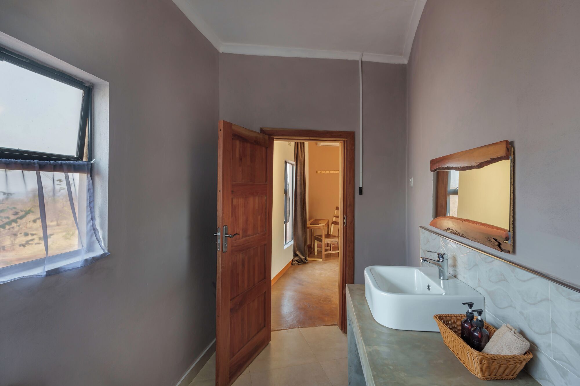 A bathroom with a sink, mirror, and window.